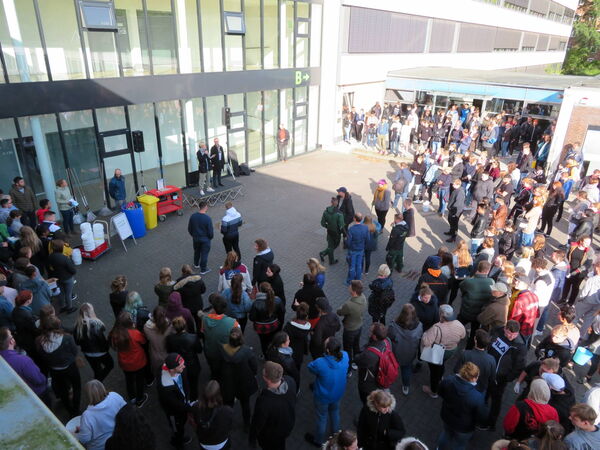 Vor Beginn des Kippensammelns wird eine Rede außen im Eingangsbereich vor den Schülerinnen und Schülern gehalten.
