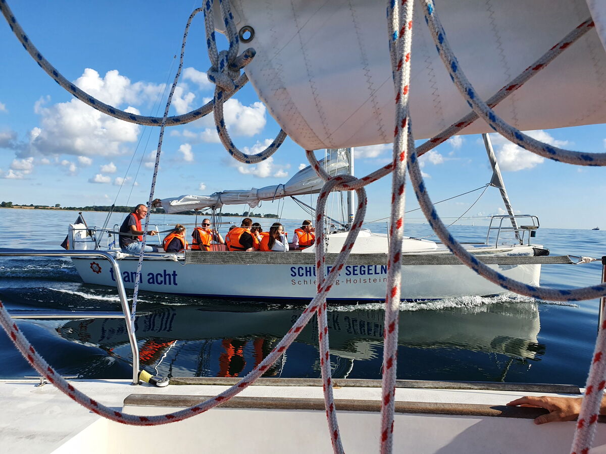 Auf dem Wasser mit Schwimmwesten und gerefftem Segel.