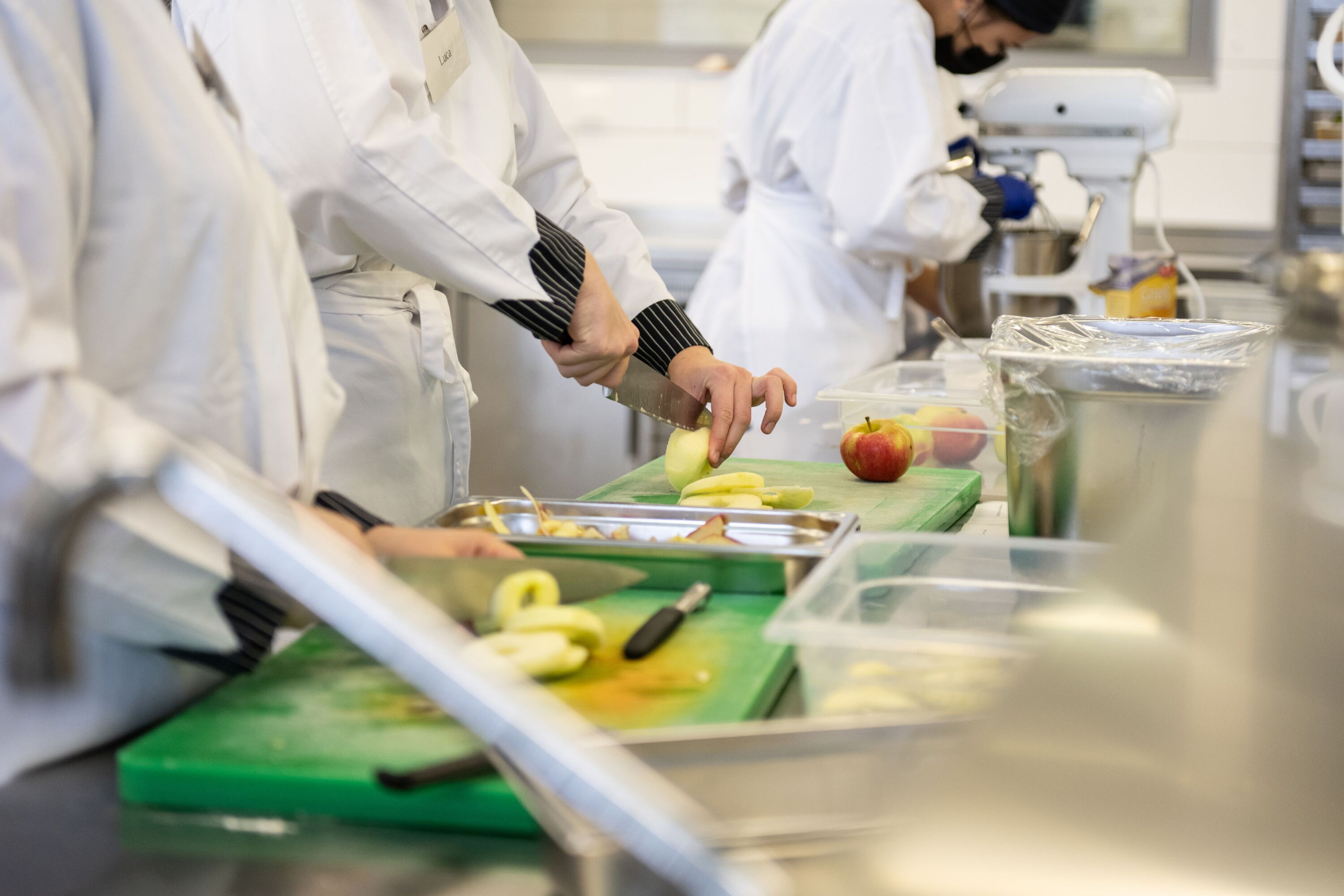 Auf Schneidebrettern werden Obst wie Äpfel von Schülerinnen geschnitten.