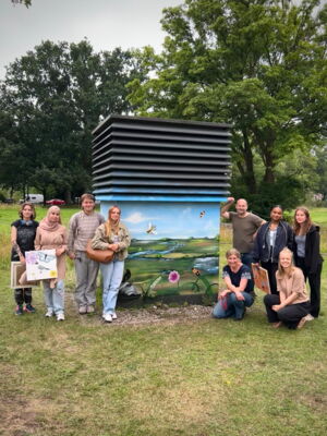 Eine Gruppe von Schülerinnen und Schülern steht vor der besprühten Entlüftungsanlage.