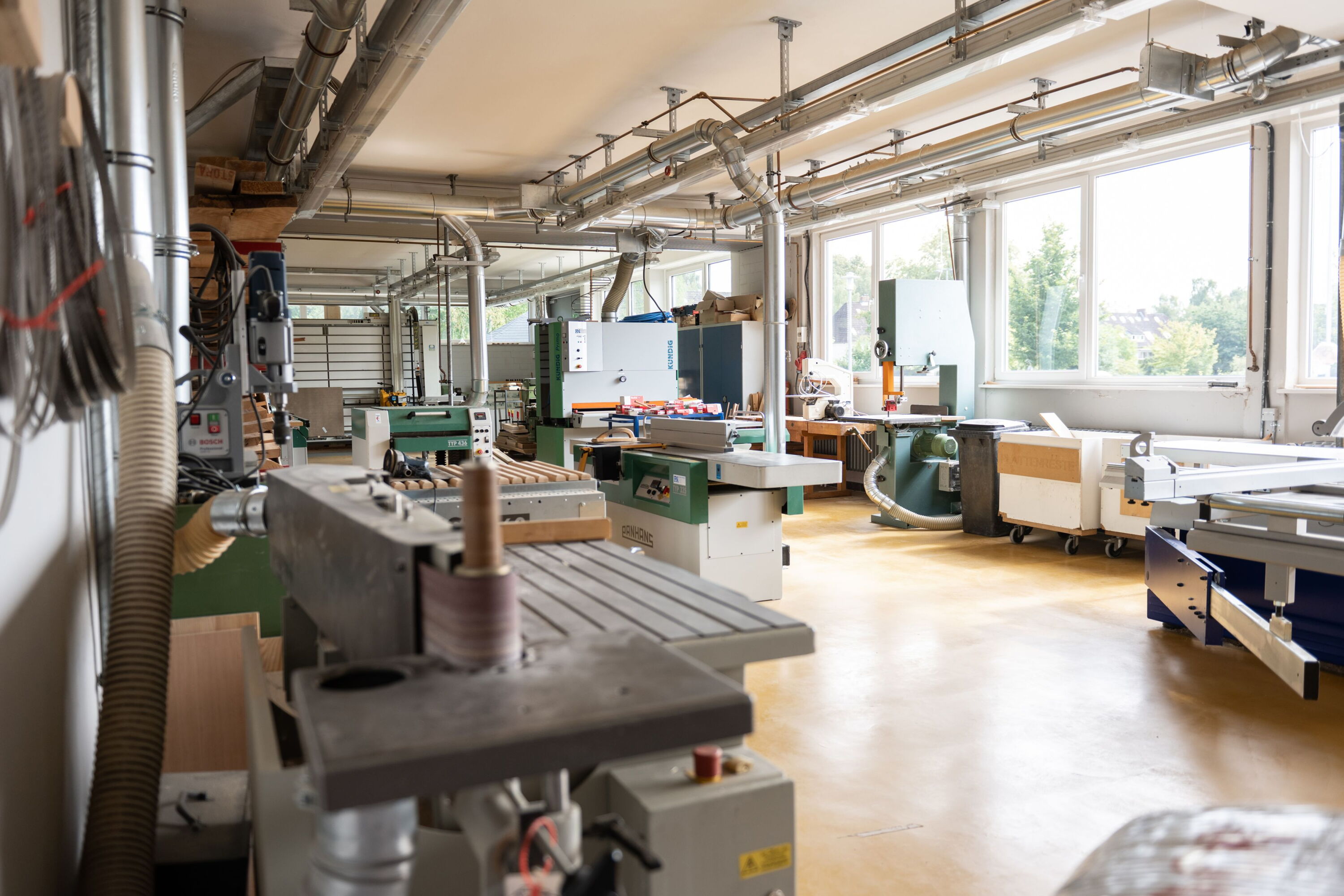 Blick in die Maschinenhalle, mit Bandschleifer, Fräse, Abrichthobel und anderen professionellen Holzbearbeitungsgeräten.