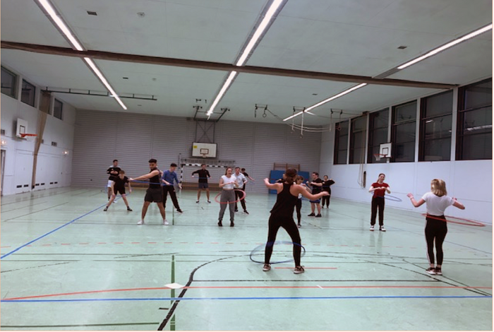 Hallensport mit Reifen von Schülerinnen und Schülern.