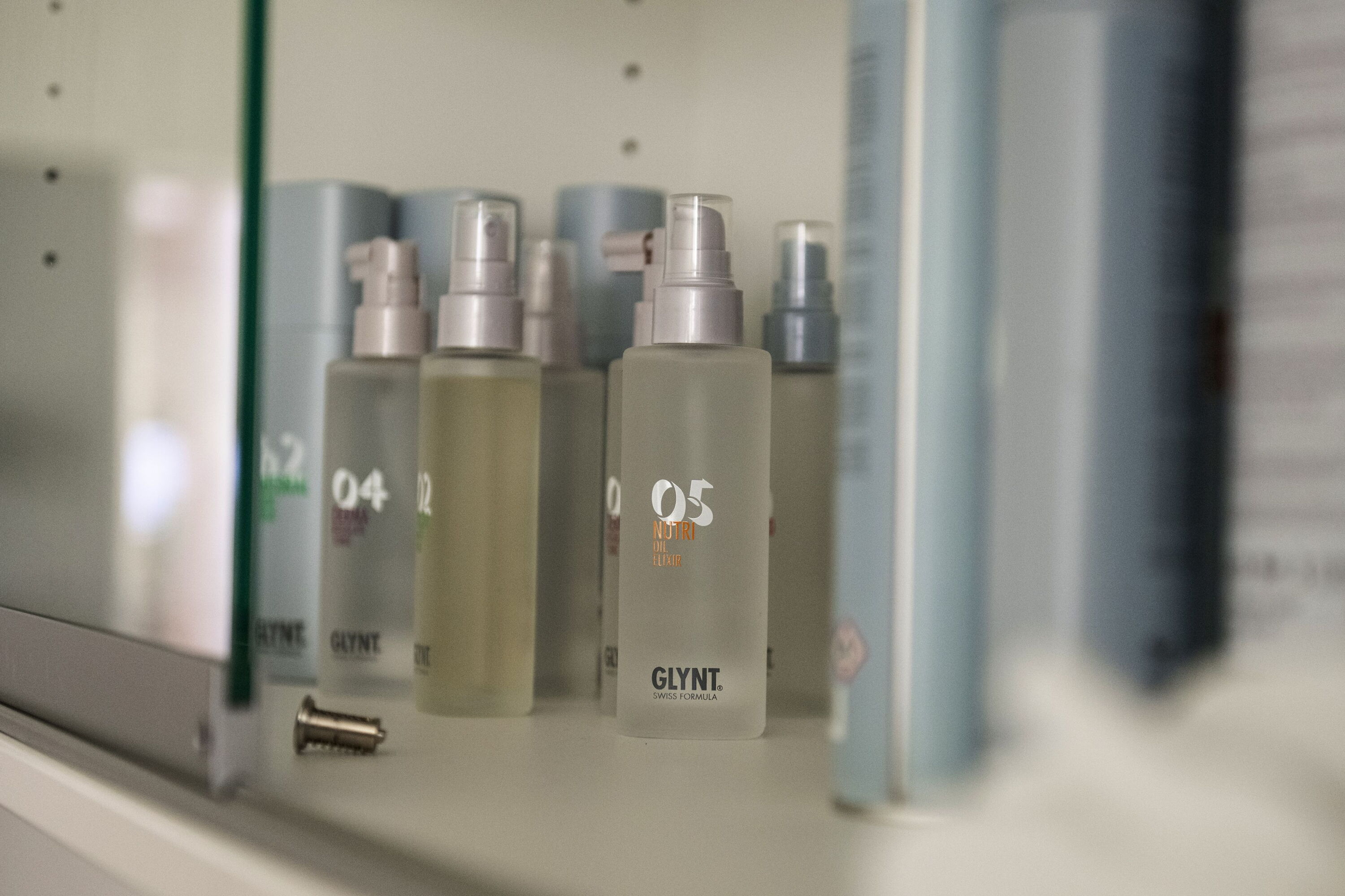 In einem Schrank stehen edel anmutende Glassprühflaschen der Marke O5 Glynt.