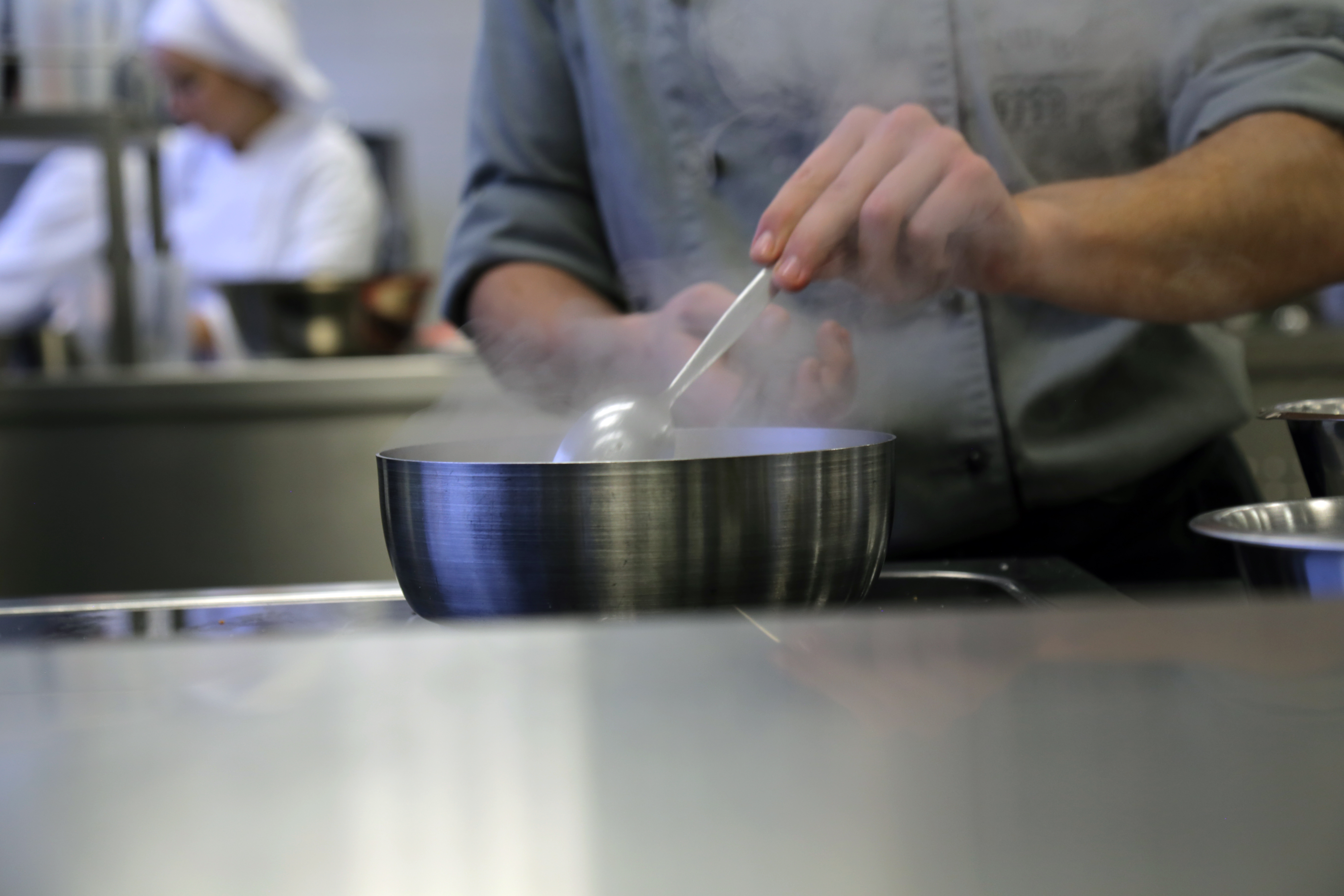 Mit einem Löffel wird in einer Pfanne gerührt, es dampft.