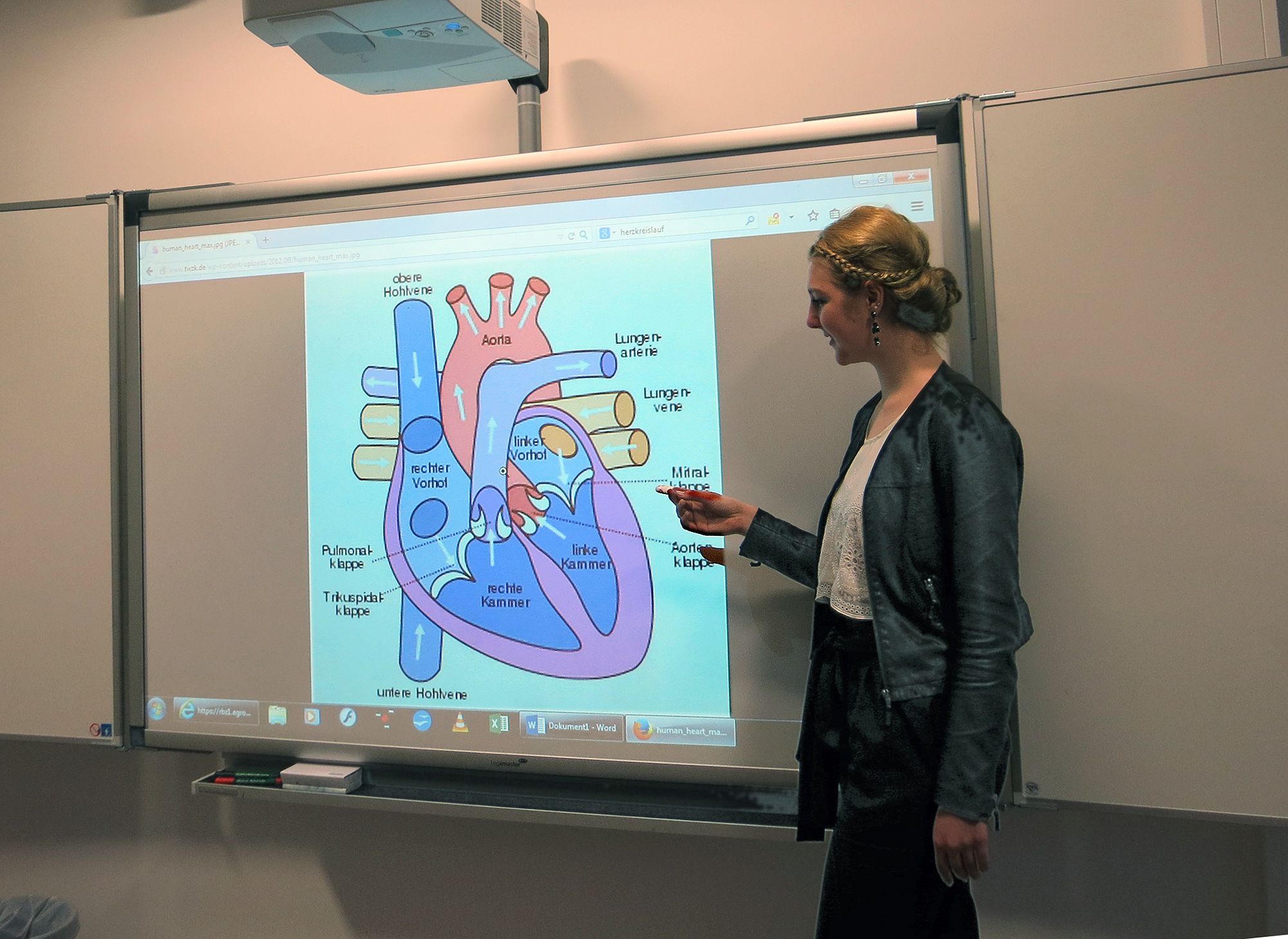 Schülerin hält ein Referat zum Thema Herz, welches auf der Leinwand zu sehen ist.